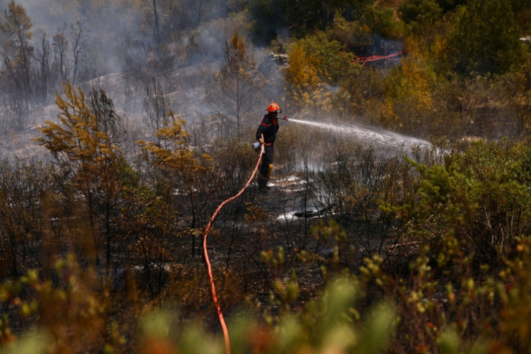 Un pompier arrose la végétation brûlée dans le Var, sud-est de la France, le 22 juillet 2026 ( POOL / Manon Cruz )