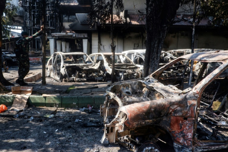 Des carcasses de voitures incendiées près du conseil provincial et local de Makassar, principale ville indonésienne des Célèbes du sud théâtre de manifestations qui ont dégénéré après la mort d'un taxi-moto écrasé par un véhicule de police, le 30 août 2025 Cars and the Makassar City Council building, which were set on fire the previous night during a protest, are seen in Makassar, South Sulawesi, on August 30, 2025. At least three people were killed by a fire started by protesters at the council building in eastern Indonesia's Makassar city, a local official told AFP on August 30, after demonstrations across the country following the death of a motorcycle taxi driver hit by a police vehicle. ( AFP / DAENG MANSUR )