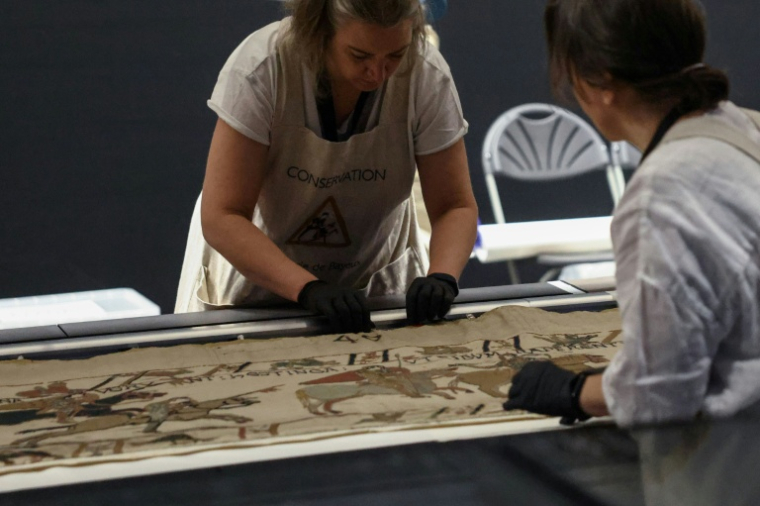 Des employées préparent la tapisserie de Bayeux présentée aux médias au British Museum, le 17 juillet 2026 à Londres ( AFP / Toby Shepheard )