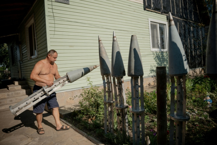 L'agriculteur ukrainien, Petro Pylypaka, transporte les restes de missiles russes dans la cour de sa maison du village de Ruski Tyshky, le 15 juillet 2025 dans la région de Kharkiv ( AFP / Ivan SAMOILOV )