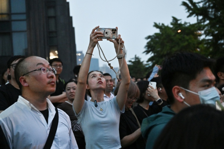 Des personnes rassemblées pour regarder l'arrivée du cortège du président américain Donald Trump à Pékin, le 13 mai 2026 ( AFP / Pedro PARDO )