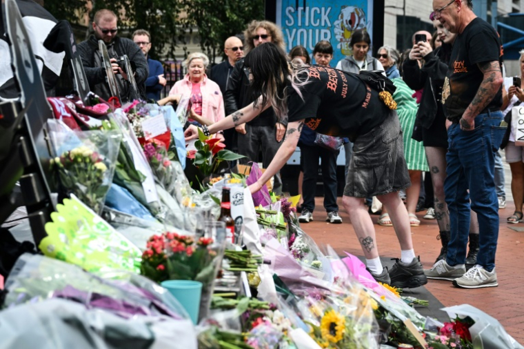 Des fans se reccueillent devant un mémorial improvisé sur le pont Black Sabbath, en hommage à l'auteur-compositeur-interprète britannique Ozzy Osbourne, au lendemain de son décès, le 23 juillet 2025 à Birmingham, dans le centre de l'Angleterre ( AFP / JUSTIN TALLIS )
