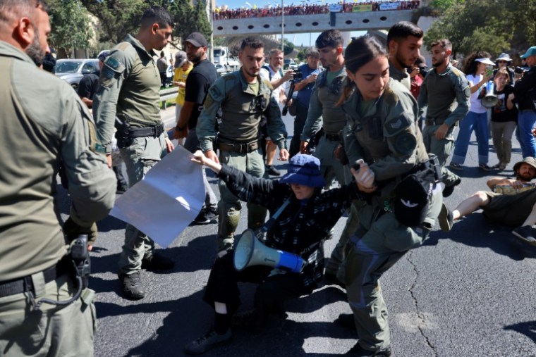 Des membres des forces de sécurité évacuent une personne manifestant à Jérusalem pour réclamer la libération des otages retenus à Gaza, le 17 août 2025 ( AFP / Menahem Kahana )