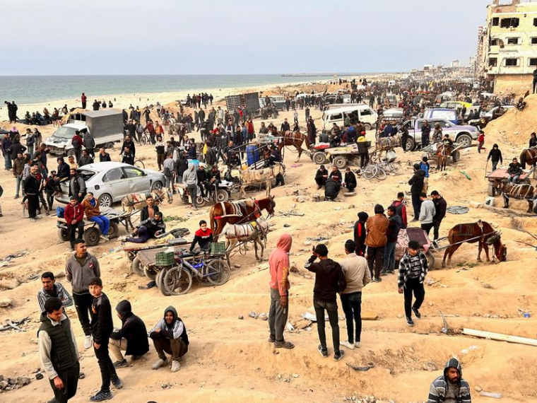 Des Palestiniens attendent l'arrivée de camions transportant des sacs de farine, près d'un point de contrôle israélien, dans la ville de Gaza