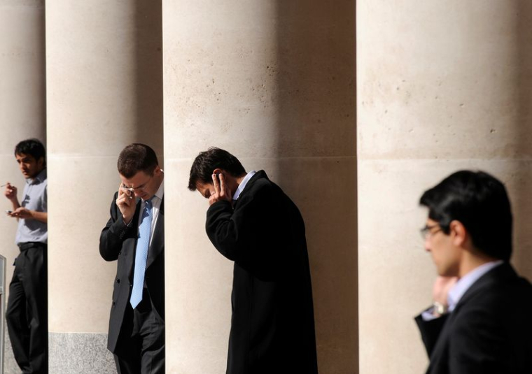 Des employés de la ville passent des appels téléphoniques devant la Bourse de Londres, sur Paternoster Square, dans la City de Londres