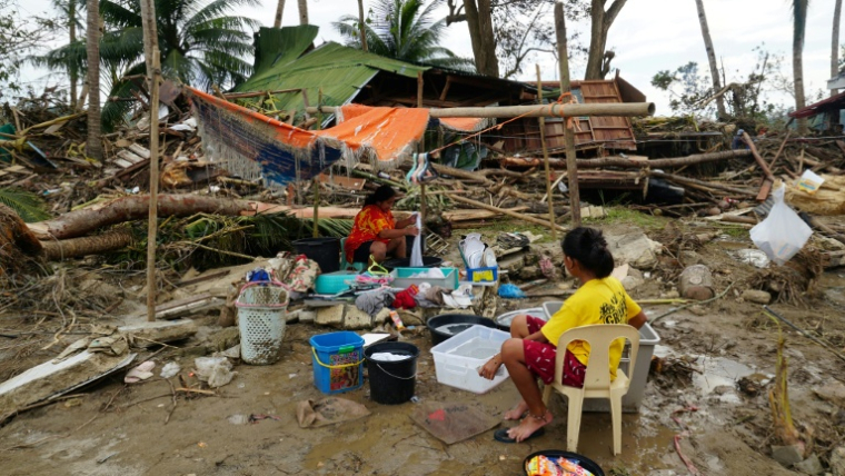 Des habitants près de leur maison détruite par le passage du typhon Rai, le 21 décembre 2021 à Loboc, dans la province de Bohol, aux Philippines ( AFP / Cheryl BALDICANTOS )