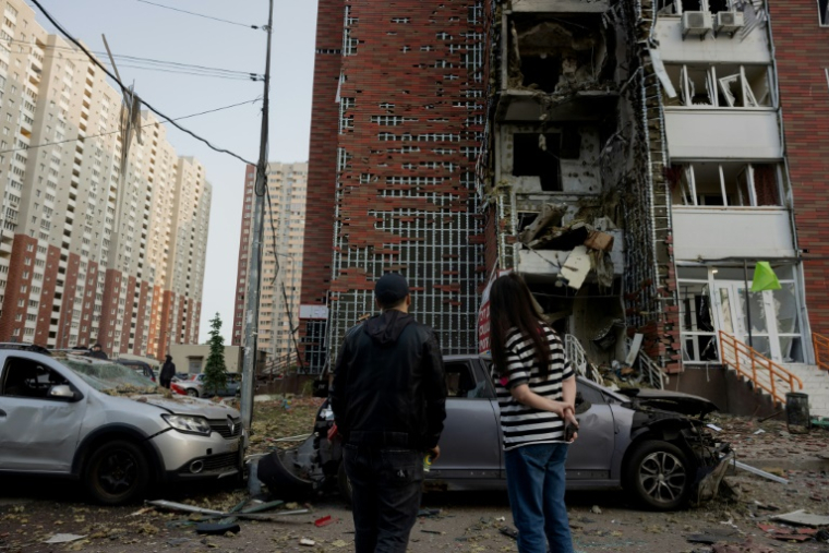 Des habitants devant un immeuble résidentiel touché par des frappes russes à Kiev, le 10 juin 2025 en Ukraine ( AFP / Tetiana DZHAFAROVA )
