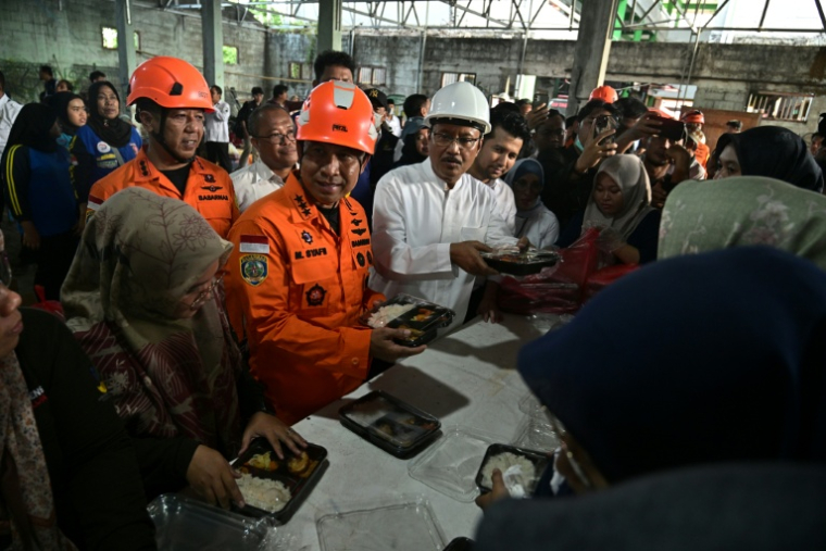 Mohammad Syafii (C), chef de l'Agence nationale de recherche et de sauvetage de l'Indonésie, accompagné de Saifullah Yusuf (centre D), ministre des Affaires sociales, inspecte une distribution de nourriture pour les proches des écoliers portés disparus après l'effondrement de l'école religieuse islamique Al Khoziny à Sidoarjo, dans la province de Java oriental, le 1er octobre 2025 ( AFP / Juni KRISWANTO )