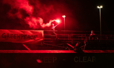 Un militant tient une fusée éclairante à côté d'une banderole "Greenpeace", lors d'une opération visant à bloquer le cargo Mikhail Dudin à Dunkerque, le 2 mars 2026 dans le Nord ( AFP / Sameer Al-DOUMY )