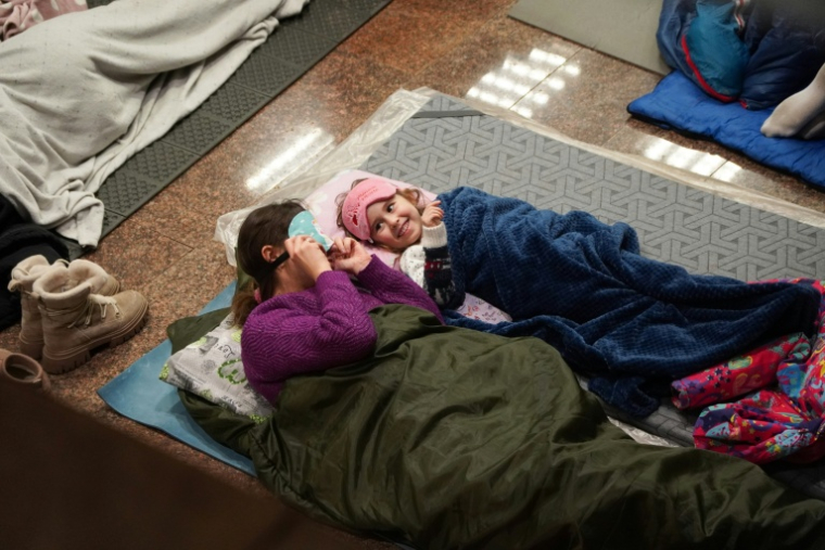 Une femme et un enfant se réfugient dans une station de métro pendant une attaque aérienne russe, à Kiev, tôt le matin du 3 février 2026, dans le contexte de l'invasion russe de l'Ukraine. ( AFP / Serhii Okunev )