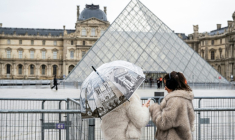 Des visiteuses devant le musée du Louvre et la pyramide conçue par l'architecte sino-américain Ieoh Ming Pei, le 12 janvier 2026 à Paris ( AFP / Martin LELIEVRE )
