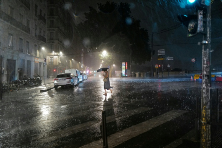 Une passante dans une rue de Lyon pendant un orage, le 16 juillet 2026 ( AFP / OLIVIER CHASSIGNOLE )