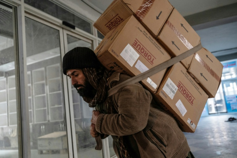 Un homme transporte des colis pharmaceutiques importés d'Inde dans une pharmacie à Kaboul, le 9 février 2026 en Afghanistan ( AFP / Wakil KOHSAR )