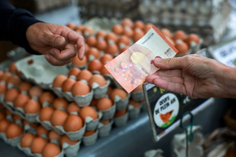 Des clients font leurs courses sur un marché local à Paris