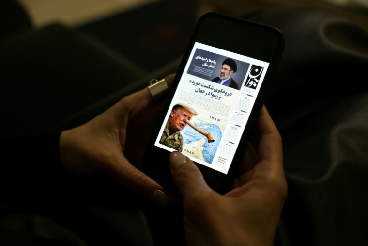 Une Iranienne lit une version numérique du journal Javan sur son téléphone portable à Téhéran, le 25 mars 2026 ( AFP / - )