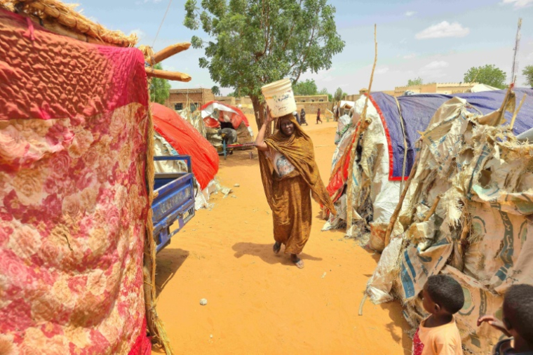 Une femme soudanaise transporte un bidon en plastique dans le camp d'Al-Rahmaniyah pour personnes déplacées, près de la ville d'El-Obeid, dans la région du Kordofan du Sud, le 25 juin 2026 ( AFP / - )