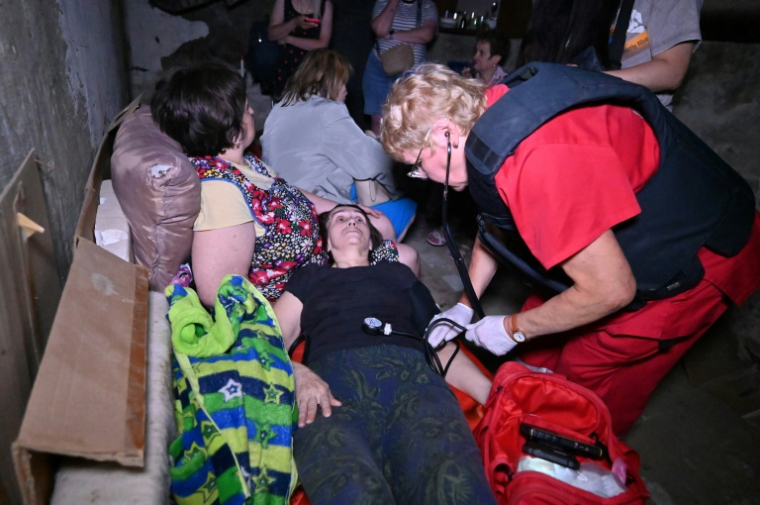 Un médecin s’occupe d’une femme allongée dans un sous-sol avec d’autres personnes pour se protéger d’une frappe de drone russe à Kharkiv en Ukraine, le 7 juillet 2025. ( AFP / SERGEY BOBOK )