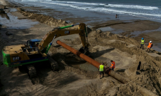 Des ouvriers raccordent une section de tuyau dans le cadre d'une expérimentation de lutte contre l'érosion marine, à Soulac-sur-Mer, en Gironde, le 10 avril 2026 ( AFP / Christophe ARCHAMBAULT )