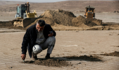 Un ingénieur irakien examine le sol tandis que des bulldozers dégagent des dunes de sable et extraient de l’argile dans le désert au sud de Samawah, le 21 décembre 2025 ( AFP / AHMAD AL-RUBAYE )
