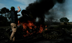 Le 16 décembre 2025, un agriculteur français jette un pneu sur un bûcher installé sur l'autoroute A63, bloquée dans les deux sens à l'échangeur de Cestas, en Gironde ( AFP / Philippe LOPEZ )