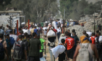 Déplacés palestiniens transportant des sacs d'aide humanitaire après une distribution à Nousseirat, dans le centre de la bande de Gaza, le 26 juillet 2025 ( AFP / Eyad BABA )