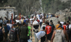Déplacés palestiniens transportant des sacs d'aide humanitaire après une distribution à Nousseirat, dans le centre de la bande de Gaza, le 26 juillet 2025 ( AFP / Eyad BABA )