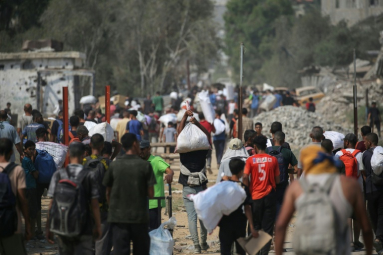 Déplacés palestiniens transportant des sacs d'aide humanitaire après une distribution à Nousseirat, dans le centre de la bande de Gaza, le 26 juillet 2025 ( AFP / Eyad BABA )