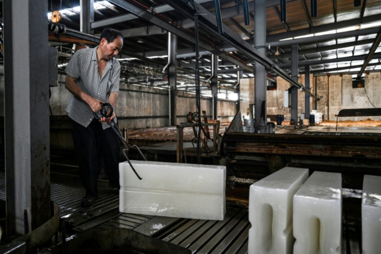 Un ouvrier transporte des blocs de glace vers un camion réfrigéré à l'usine de production de glace Feichao à Hangzhou, dans la province orientale du Zhejiang, le 9 juillet 2025 en Chine ( AFP / Hector RETAMAL )