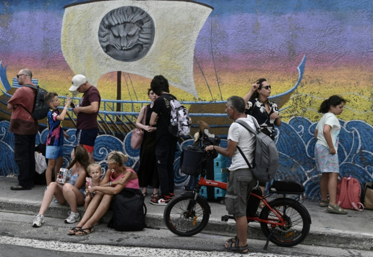 Des touristes turcs attendent dans une file d’attente devant le bureau des douanes, dans le village de Vathy, sur l’île de Samos, le 24 juillet 2026 ( AFP / Sakis Mitrolidis )