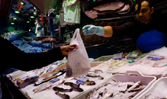 Un poissonnier tend un sac de poisson à un client dans un supermarché alors que le gouvernement espagnol annonce des mesures pour lutter contre l'inflation, à Madrid.