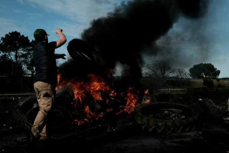 Le 16 décembre 2025, un agriculteur français jette un pneu sur un bûcher installé sur l'autoroute A63, bloquée dans les deux sens à l'échangeur de Cestas, en Gironde ( AFP / Philippe LOPEZ )