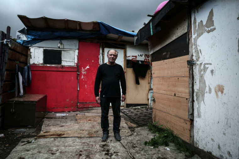 Vasile, un habitant du bidonville, pose pour une photo le 26 septembre 2025, au milieu des cabanes de Stains, en banlieue parisienne ( AFP / Thibaud MORITZ )