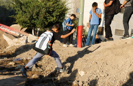Des étudiants palestiniens traversent une barrière de terre israélienne sur le chemin de l'école à Araqah