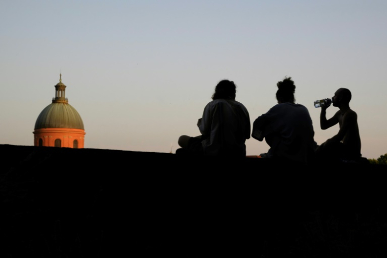 Des gens assis près des bords de la Garonne, le 20 juin 2025 à Toulouse ( AFP / Ed JONES )