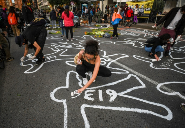 Des silhouettes peintes sur le sol simulant des cadavres, lors d'un rassemblement contre les milliers d'exécutions extrajudiciaires, devant la Juridiction spéciale pour la paix (JEP) à Bogota, le 28 juin 2021 en Colombie ( AFP / Juan BARRETO )