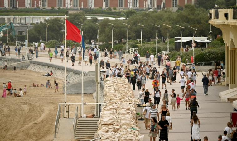 Un drapeau rouge interdisant la baignade sur la Grande plage de Biarritz, le long de laquelle marchent de nombreux promeneurs le 26 août 2025 ( AFP / Gaizka IROZ )