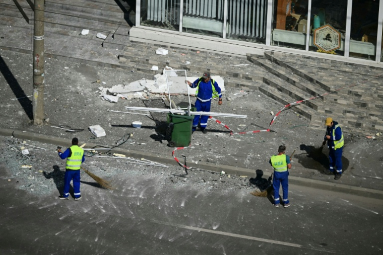 Des employés municipaux dégagent les débris de la rue après qu'un drone russe a percuté un immeuble d'habitation à Galati, le 29 mai 2026 dans l'est de la Roumanie ( AFP / Daniel MIHAILESCU )