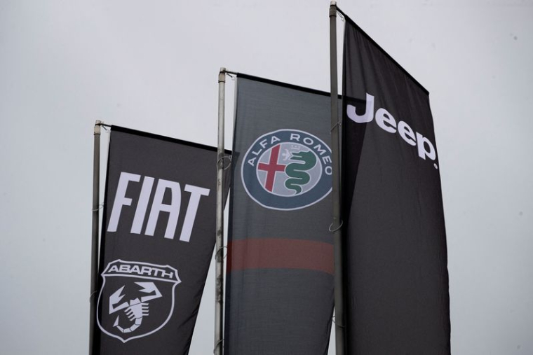 Des bannières montrant les logos de Fiat, Jeep, Abarth et Alfa Romeo sont suspendues à l'extérieur d'une concession automobile