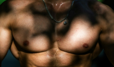 Le torse musclé d'un homme qui s'entraîne sur une aire de street workout à Paris, le 10 août 2025 ( AFP / Julie SEBADELHA )