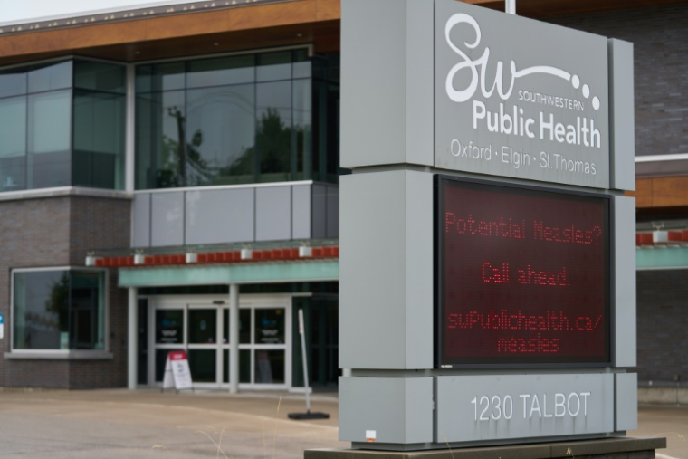 Un panneau à l'extérieur du bureau de santé publique du Sud-Ouest à St. Thomas, conseille aux patients qui soupçonnent avoir la rougeole d'appeler à l'avance avant de consulter un médecin, le 9 juillet 2025 en Ontario, au Canada ( AFP / Geoff Robins )