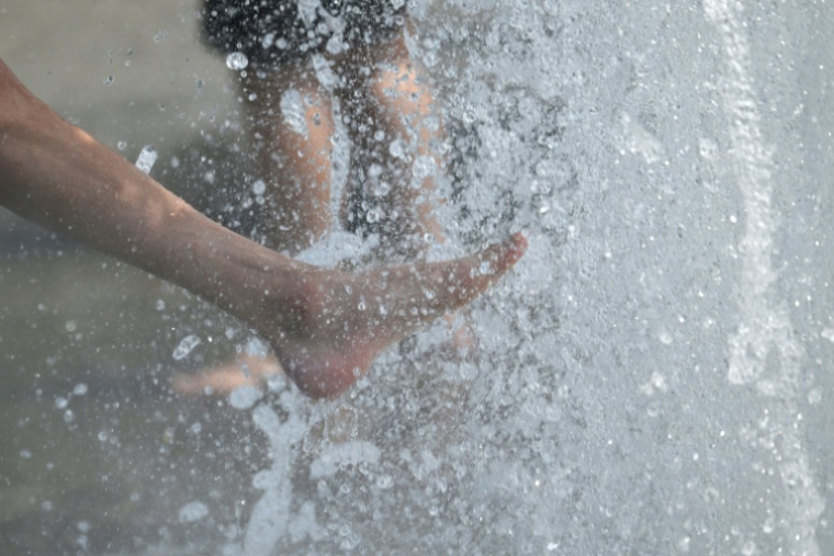 Des gens se rafraîchissent les pieds dans une fontaine de Berlin, le 28 juin 2026  ( AFP / RALF HIRSCHBERGER )