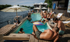 Des clients se prélassent au bord de la piscine de Foil in Paris, en bord de Seine, le 2 août 2026 ( AFP / Simon WOHLFAHRT )