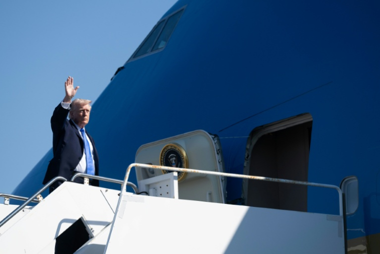 Le président américain Donald Trump salue les personnes présentes à l'aéroport de West Palm Beach en Floride, avant de monter dans Air Force One, le 23 mars 2026 ( AFP / SAUL LOEB )