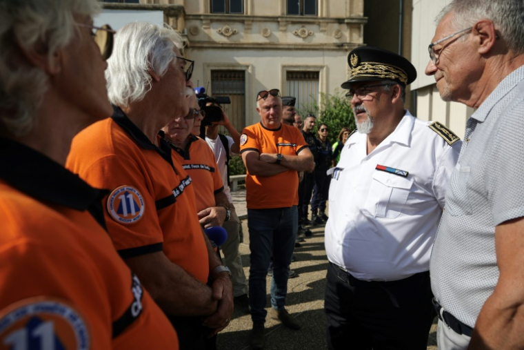 Le préfet de l'Aude Christian Pouget flanqué du maire de Lézignan-Corbières (D), rencontre les membres du Comité municipal des incendies de forêt à Lézignan-Corbières dans l'Aude le 7 août 2025 ( AFP / Valentine CHAPUIS )