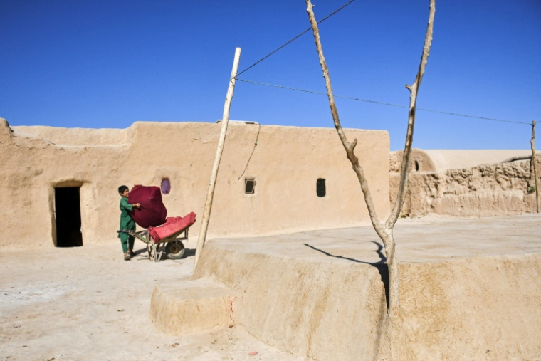 Un enfant afghan, qui fait partie des nombreux déplacés climatiques, place des effets personnels dans une brouette dans le village de Bolak, dans le nord de l'Afghanistan, le 10 juillet 2025 ( AFP / Atif Aryan )