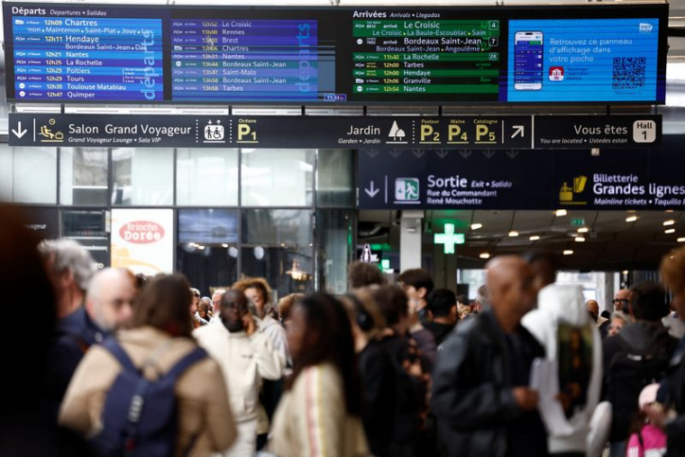 Des passagers attendent à l'intérieur du hall de départ de la gare Montparnasse à Paris