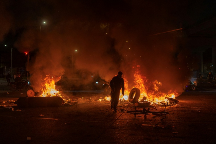 Un homme jette un pneu dans un feu lors d'affrontements avec la police, alors que des manifestants protestent contre les résultats préliminaires du second tour de l'élection présidentielle à Bogotá, en Colombie, le 21 juin 2026 ( AFP / Diego Cuevas )