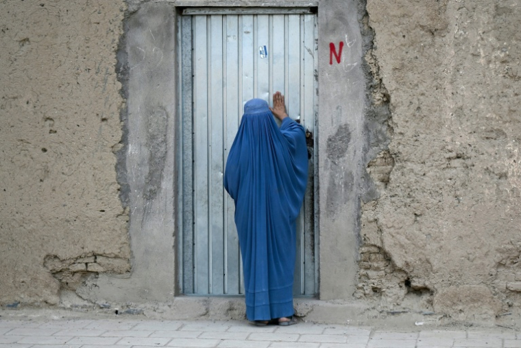 Une Afghane en burqa frappe à la porte d'une maison, à Kandahar, en Afghanistan, le 28 septembre 2026 ( AFP / Sanaullah SEIAM )