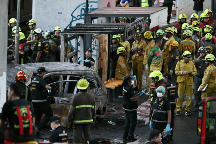 Des pompiers et policiers sur le site d'une collision entre un train de marchandises et un bus à Bangkok, le 16 mai 2026 en Thaïlande ( AFP / Lillian SUWANRUMPHA )