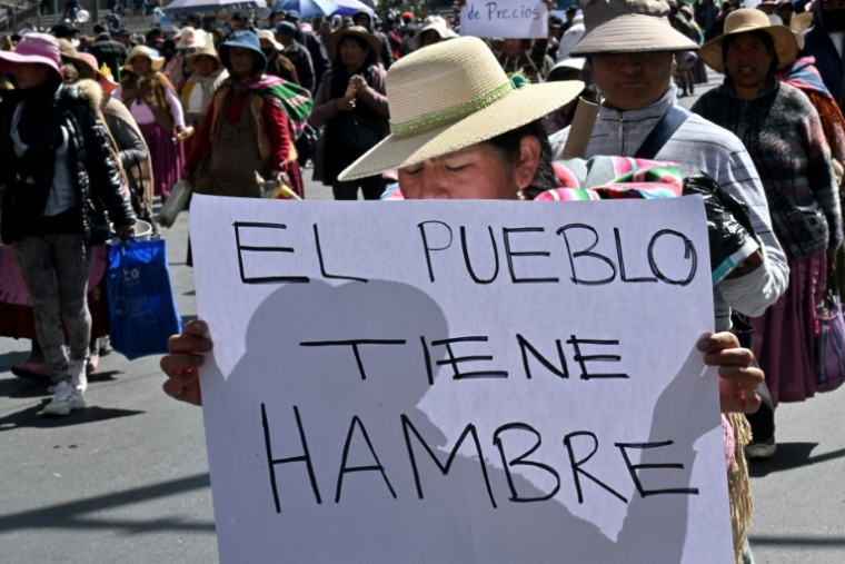 Une paysanne Aymara montre une pancarte avec le message "Le peuple a faim" lors d'une marche pour demander au gouvernement de Luis Arce de trouver rapidement une solution à la crise économique, à La Paz, le 9 juin 2025. ( AFP / AIZAR RALDES )